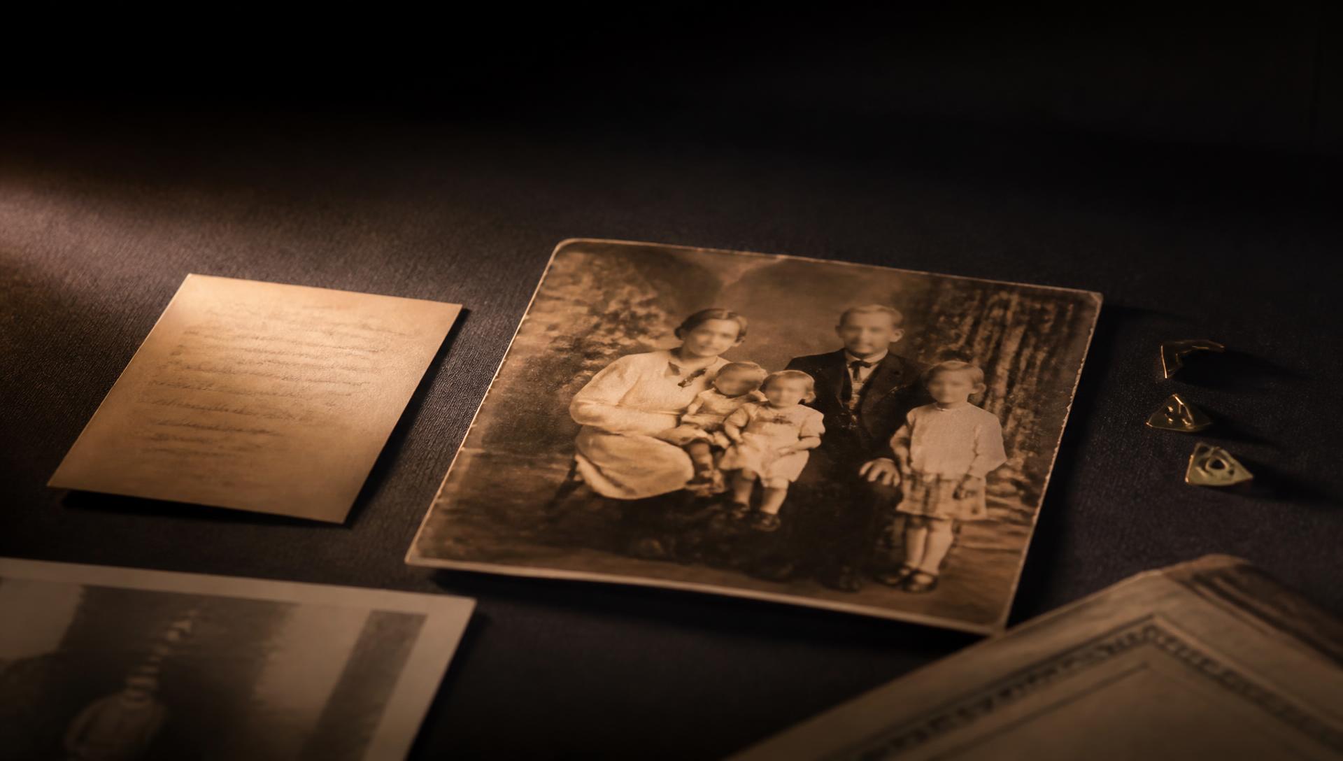 A single aged family photograph beside a handwritten note in a pool of warm light